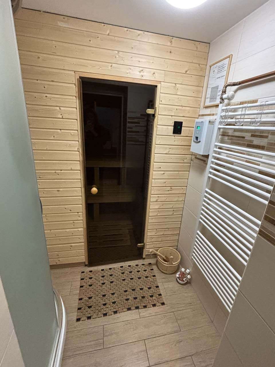 Vstup do sauny se skleněnými dveřmi a sprcha